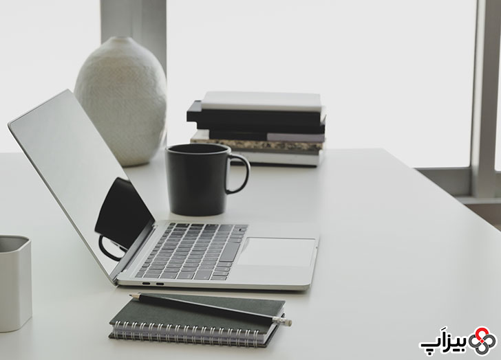 لپ‌تاپ و دفترچه روی میز کار